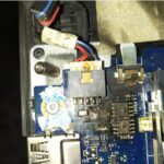 Close-up of a laptop motherboard showing burn damage around the charging port connector caused by overheating or electrical failure.